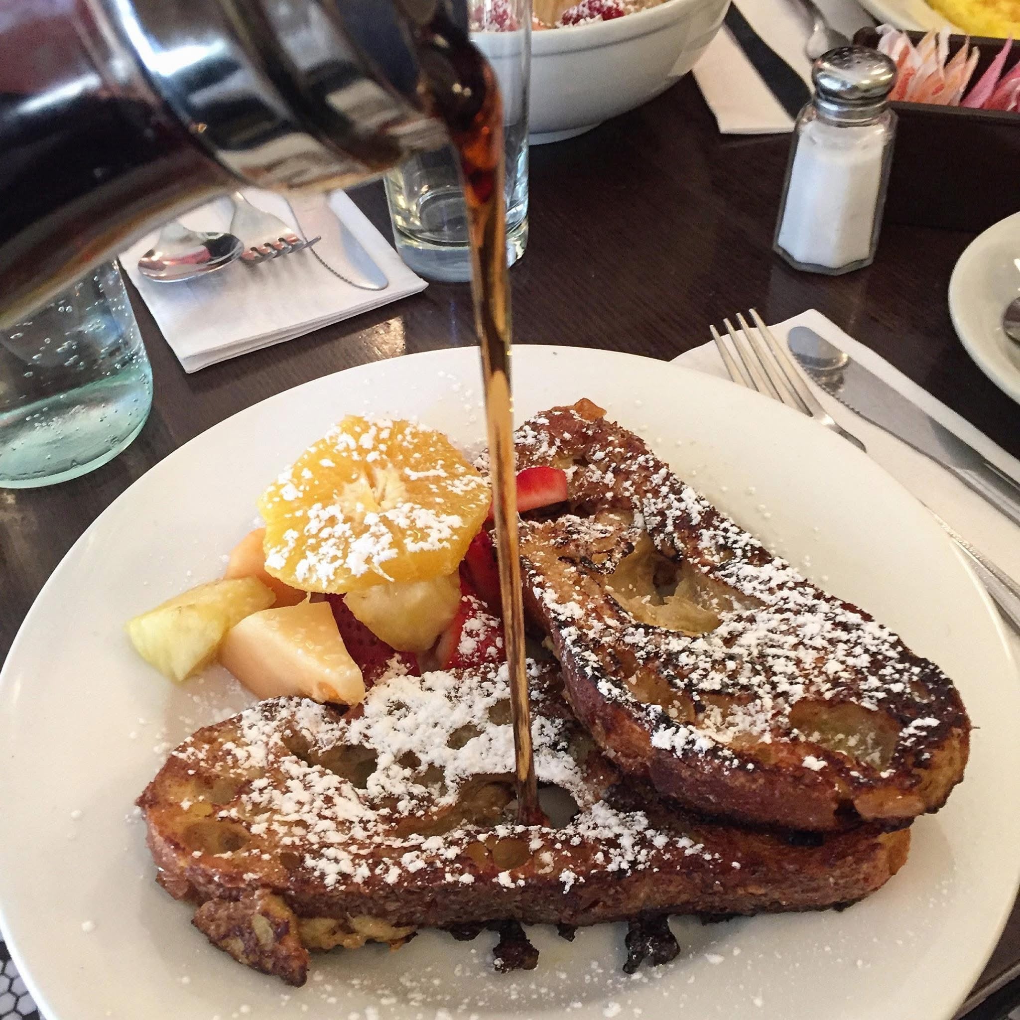 Maple syrup poured over french toast with fresh fruit at Fiat Cafe